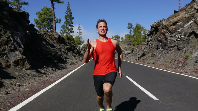 Running man sprinting fast at speed. Male athlete runner sprinter training on road outdoors during workout. Strong male fitness model training outside for in beautiful nature. Strong athletic man.