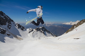 Naklejka na ściany i meble Snowboard jump on mountains. Extreme winter sport.