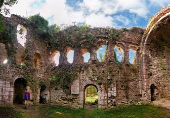 Ruins of the ivy clad Castle, a 9th century fortification situated near Gagra, Abkhazia, set against a glorious blue sky with cumulus clouds