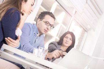 Fototapeta premium Successful business people interacting, discussing and sharing ideas in bright modern office. Teamwork concept. Focus on man in the middle, Lens flare effect