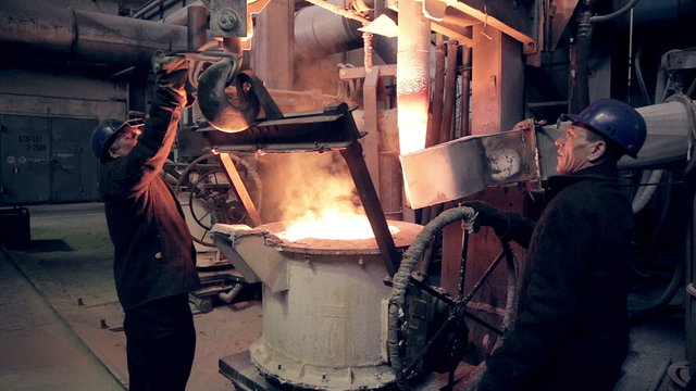 Worker on steel plant operates with  molten metal. HD.