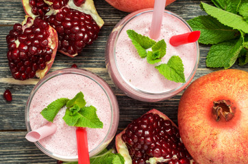 Pomegranate smoothie in glasses on wood background