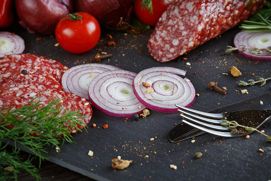Sliced salami with vegetables, onions and spicy herbs