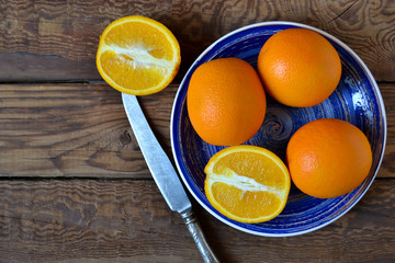 Fresh, juicy orange on the plate on a wooden background