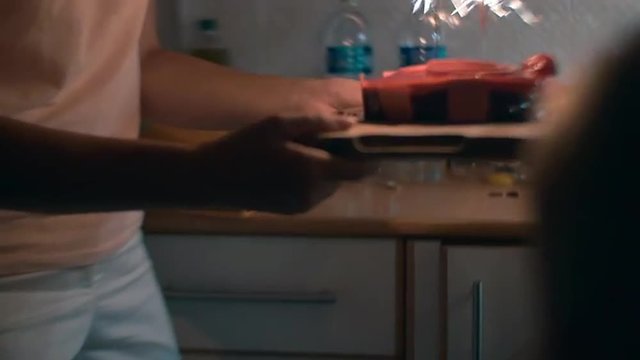 Slow motion steadicam shot of mother carrying birthday cake with sparklers and holding sons hand. Home video imitation of family celebration