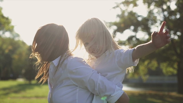 Daughter riding at mother in a city park at sunset.