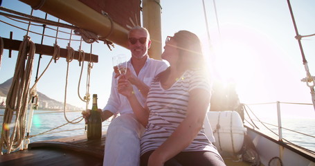 Mature couple with celebratory champagne on a sunset yacht cruise