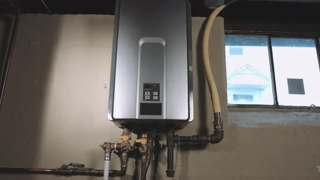 a front angle wider shot of camera moving forward and back on tankless water heater in the basement