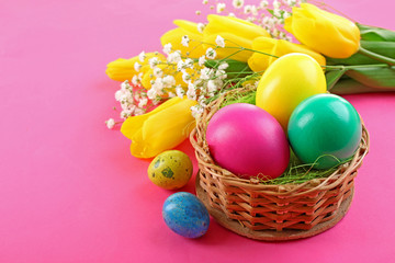 Multicoloured Easter eggs and tulips on pink background