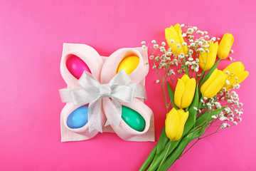 Multicoloured Easter eggs and tulips on pink background