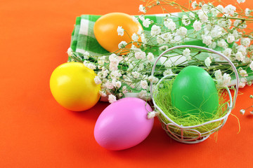 Fototapeta na wymiar Easter eggs and tulips on napkin, orange background