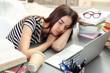Young woman fell asleep while using laptop at the table