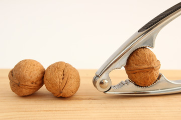 English or Persian walnuts and metal nutcracker on a wooden background.