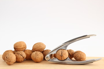 English or Persian walnuts and metal nutcracker on a wooden background.