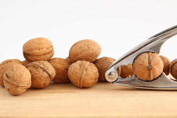 English or Persian walnuts and metal nutcracker on a wooden background.