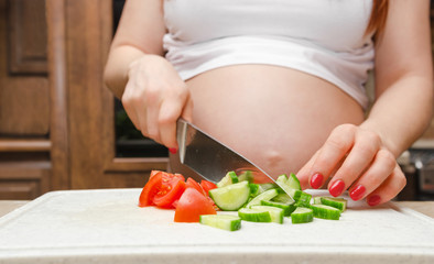 Pregnant woman cut fresh vegetables for salat close up