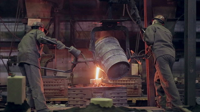 Worker on steel plant operates with molten metal. HD.