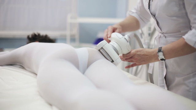 Health and beauty: Girl in specific tights is massaged for reducing cellulite with electronic massage system. Slider camera movement to forward