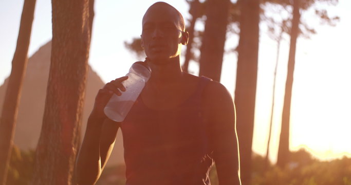 African decent athlete drinking water after a fitness achievement