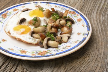 fried eggs on rustic table with mushrooms