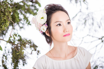 Portrait of pensive Chinese woman with flowers in hair