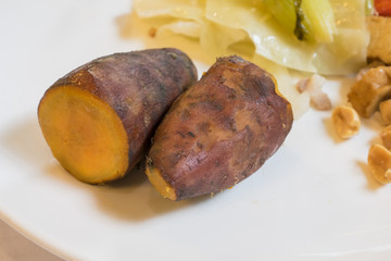 The close up of delicious sweet potato with food on white plate.