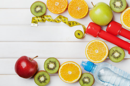 Diet plan, menu or program, tape measure, water, dumbbells and diet food of fresh fruits on white background, weight loss and detox concept, top view