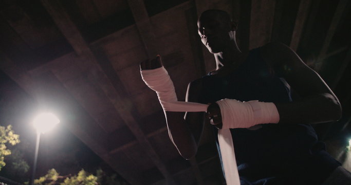African decent boxer wrapping his hands with adhesive tape