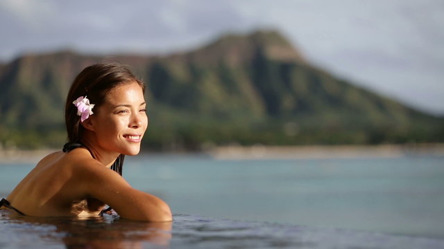 Vacation woman swimming at infinity pool on Hawaii. Beautiful asian young female adult enjoying happy holiday travel at Waikiki beach in Honolulu city, Oahu, Hawaii, USA. Summer destination holidays.