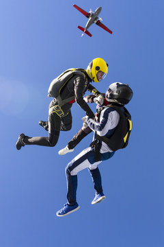 Two girls and a guy skydivers jump out of an airplane.