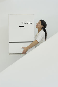 Woman carrying boxes downstairs side view