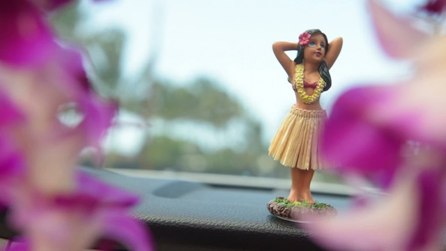 Hawaii travel car - Hula doll dancing on dashboard and lei during road trip.