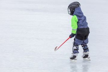 Little boy skating and playing hockey