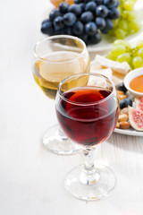 glasses with wine and snacks on white table
