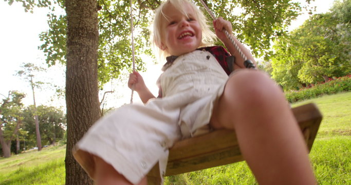 Playful boy pushing his little brother on swing at park