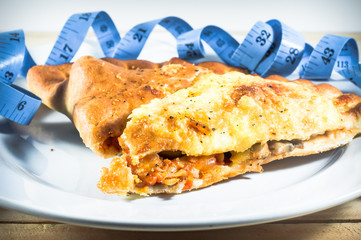 pizza puff with blue color measuring tape on white plate over wo