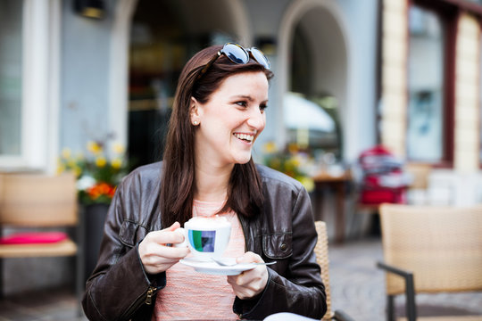 Young brunette woman sitting at a coffeeshop and relaxing