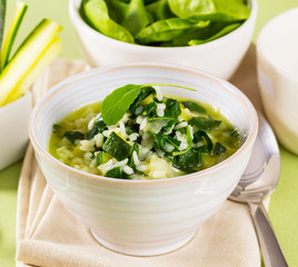 A bowl with rice, spinach and zucchini, served like a soup.