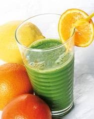 A glass of healthy juice made with spinach, orange and lemon.