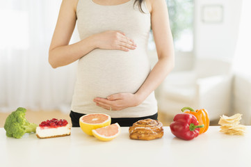 Health and unhealthy foods in front of pregnant Japanese woman 