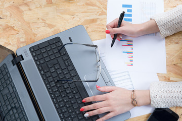 Business woman hand typing on laptop keyboard with Financial charts