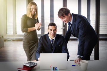 Excited business people in modern office working on project. Post processed with film and sun filter.
