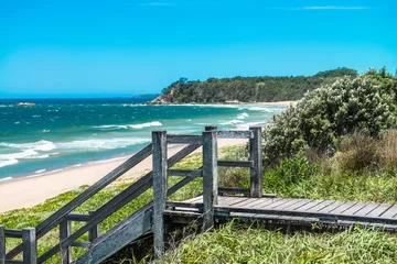 Fotobehang Stairs to paradise - Wooden stairs leading down to a deserted beach and blue ocean water. © silardtoth