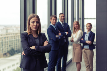 Corporate portrait of young business woman with her colleagues in background. Post processed with...