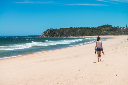 Woman walking along a completely deserted beach strip on the eastern coast of Australia.