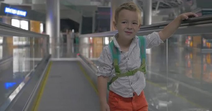 Cute little boy making faces on travelator in airport