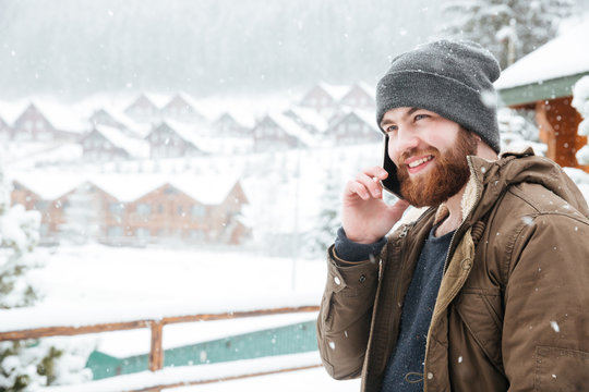 Smiling man talking on cell phone outdoors in snowy weather