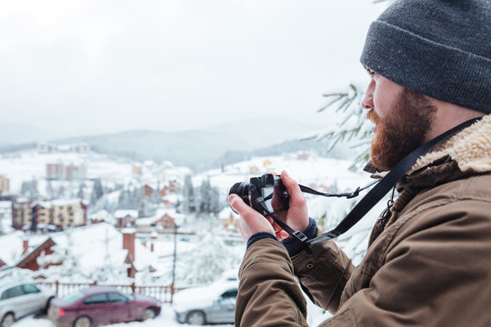 Bearded  man taking pictures of view outdoors in winter