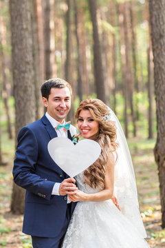 happy Groom and Bride in a park with sign as heart