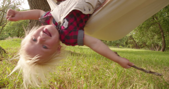 Lovely dad plays with his blond child on a hammock